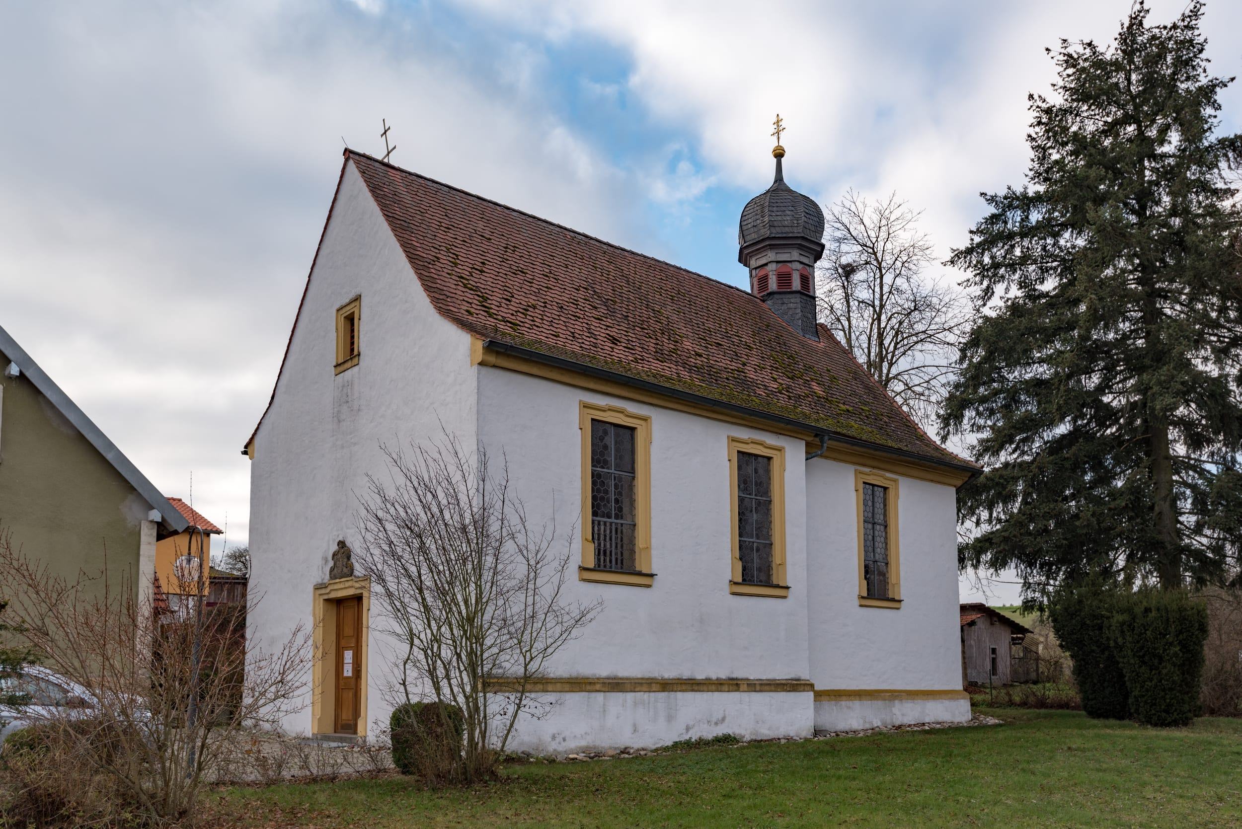Die Kapelle St. Anna mit Satteldach, Dachreiter und Zwiebelhaube in der Dorfmitte